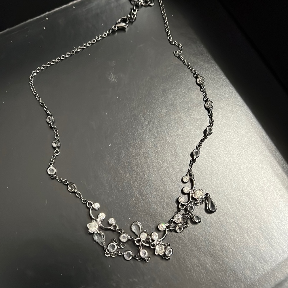 Black with clear stones necklace hangs right below neckline